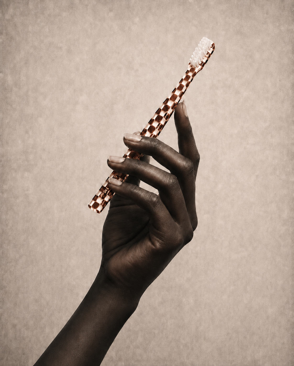 A hand holding the Anouk Damier toothbrush against a warm neutral background
