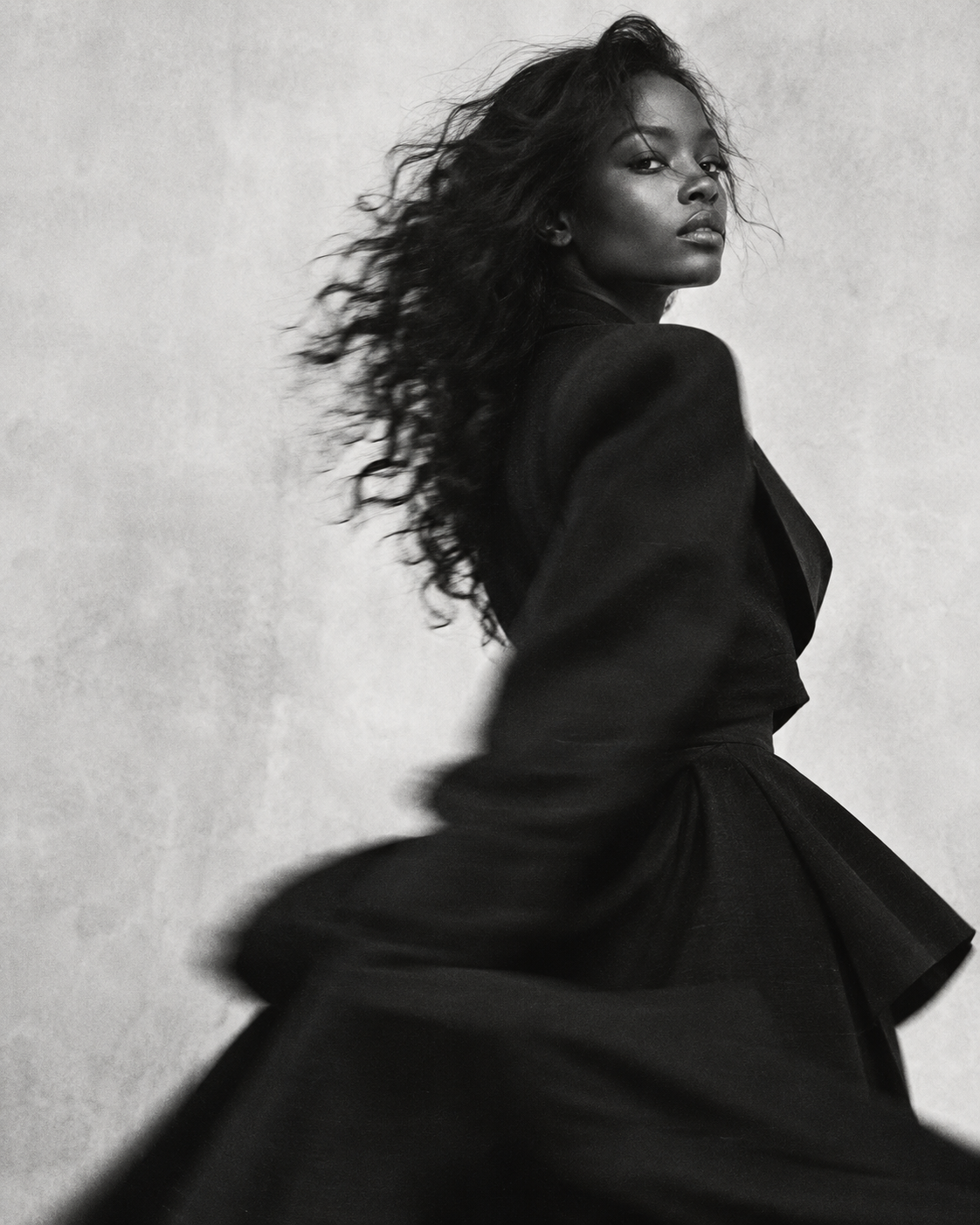 Black and white editorial portrait in sculptural black tailoring